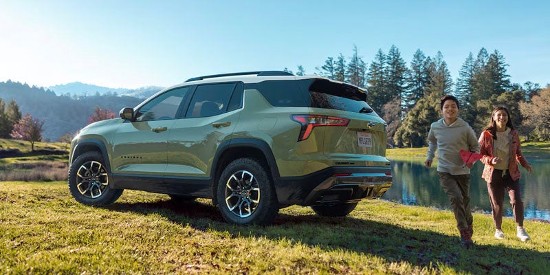 Two kids running away from a green suv.