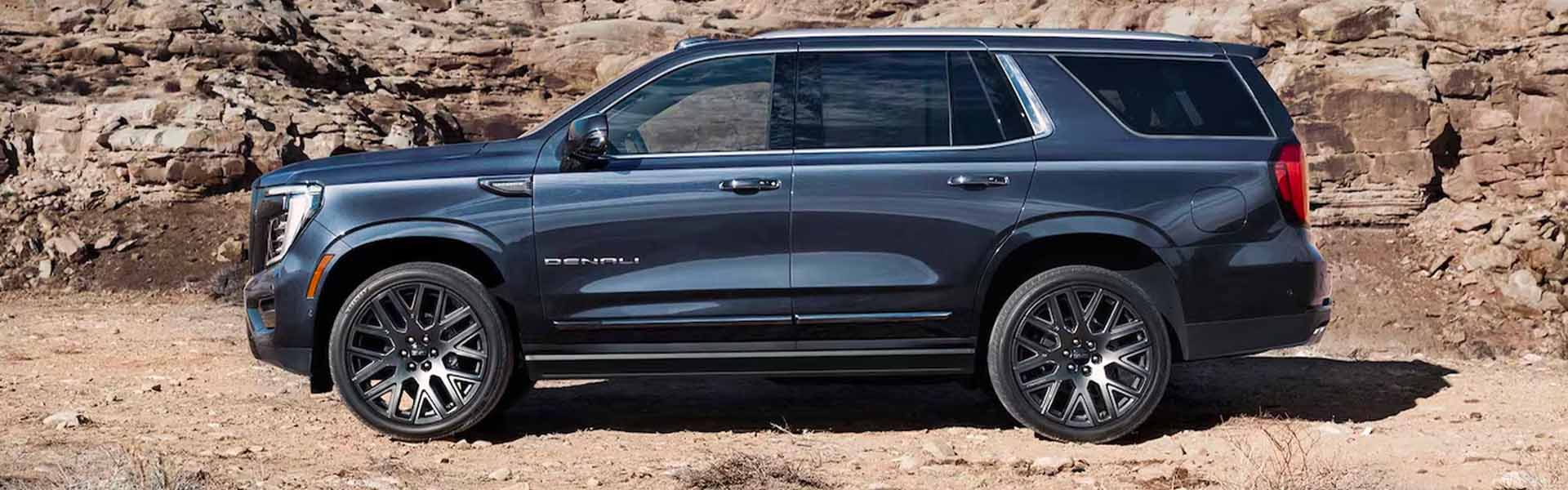 A navy suv sitting parked off-road.