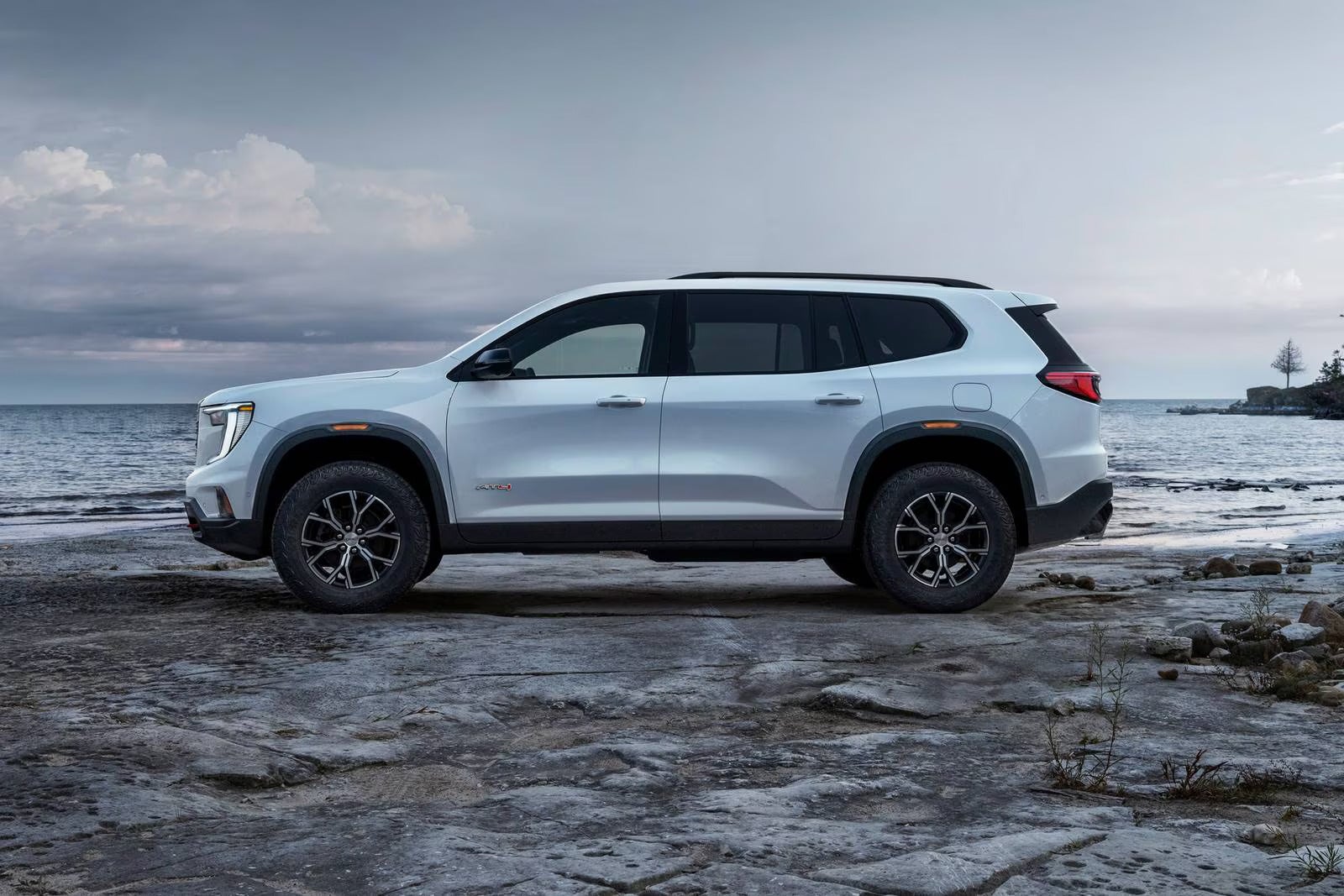 A white suv sitting parked in front of a body of water.