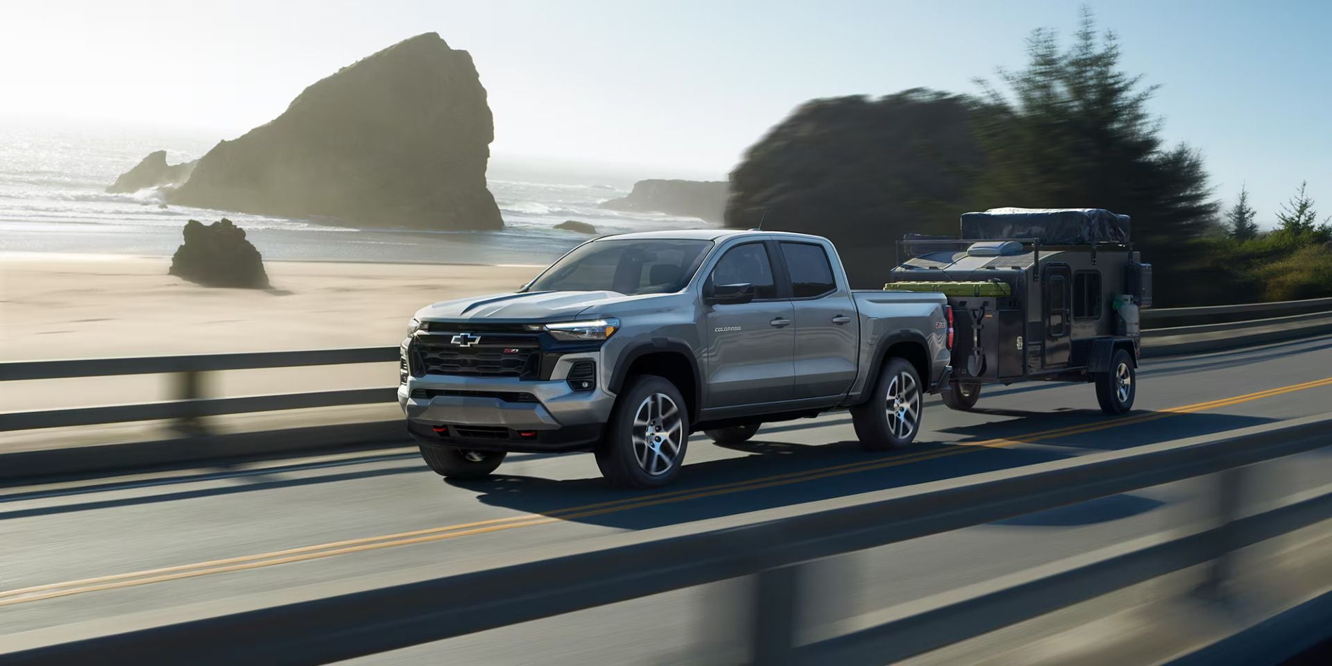 A silver truck pulling a trailer.