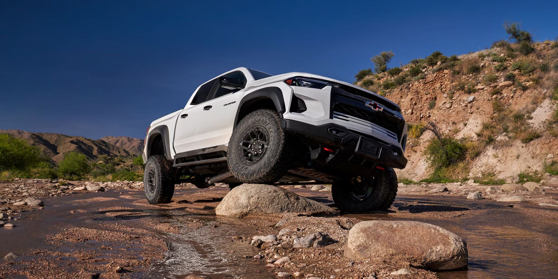 A white truck driving over a rock.