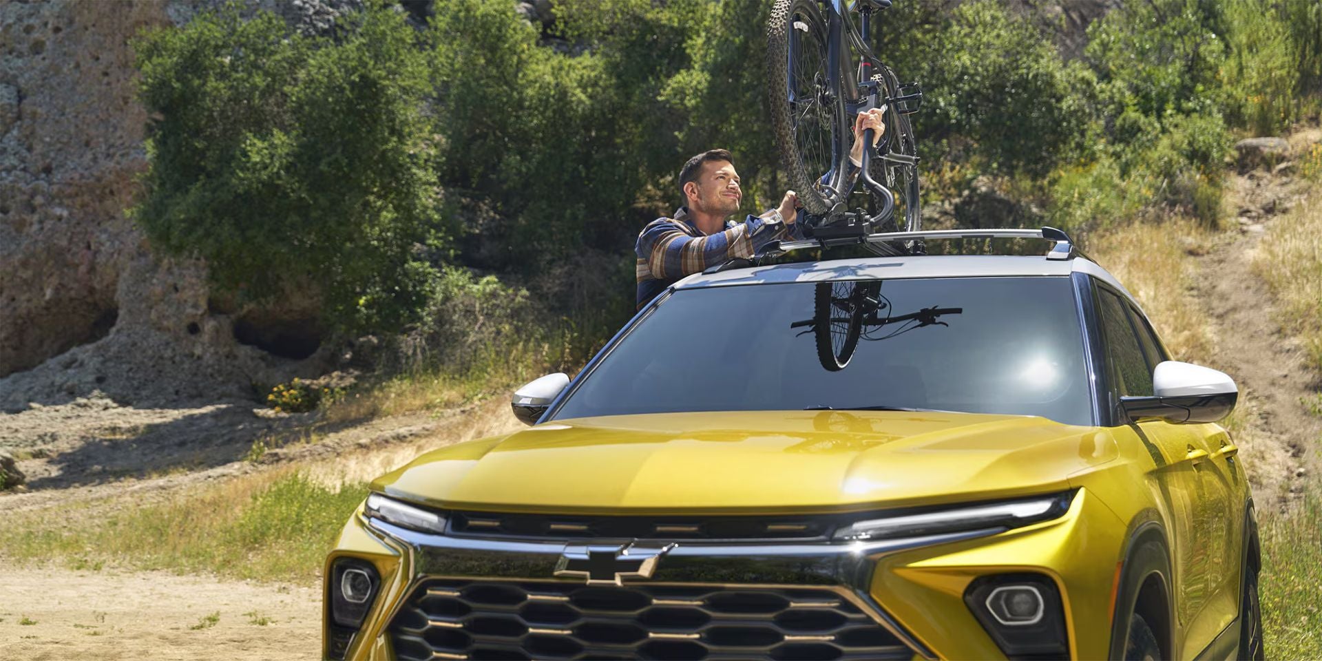 A man putting a bike on a yellow car.