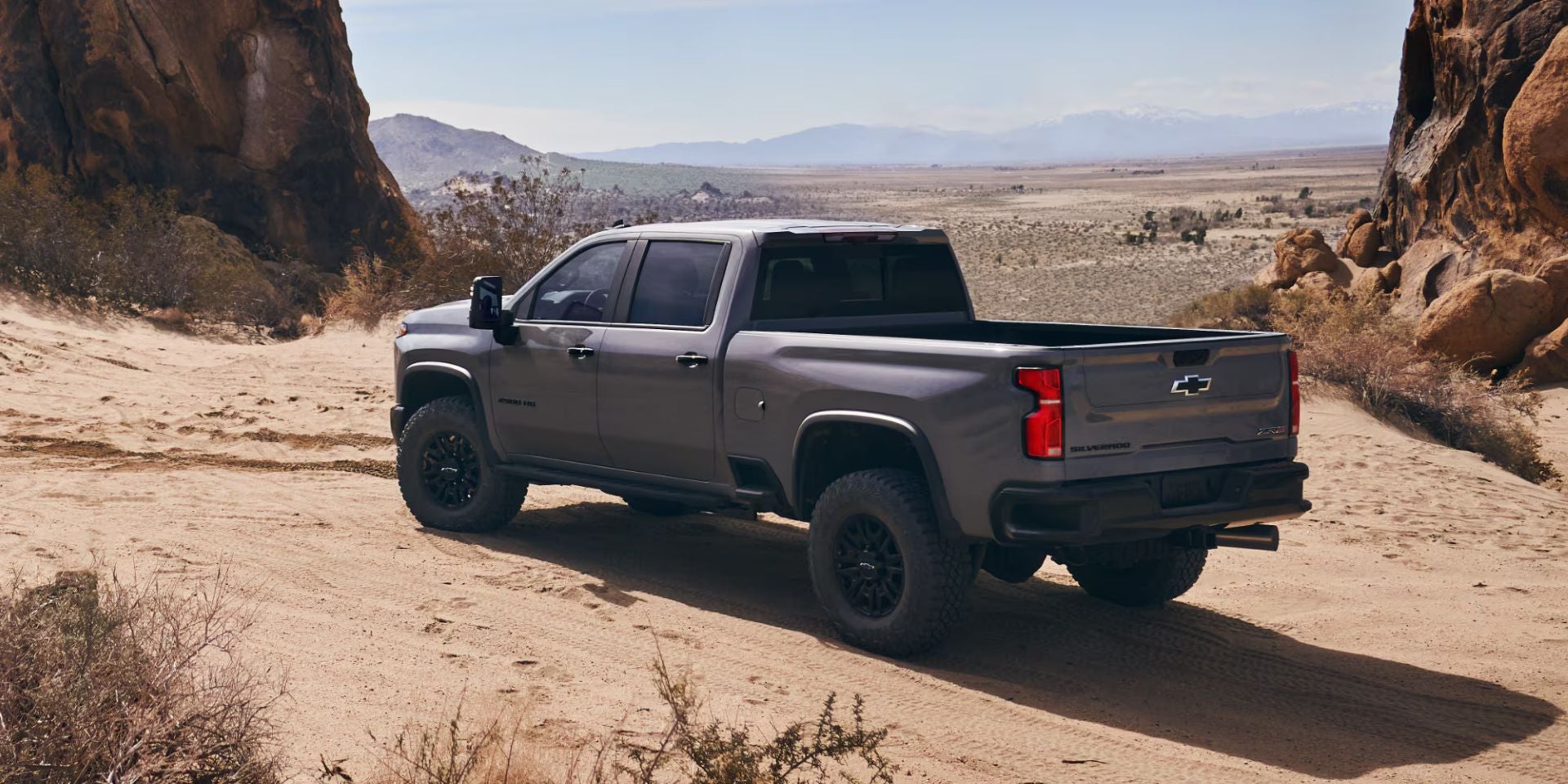 A gray truck sitting parked on a dirt path.
