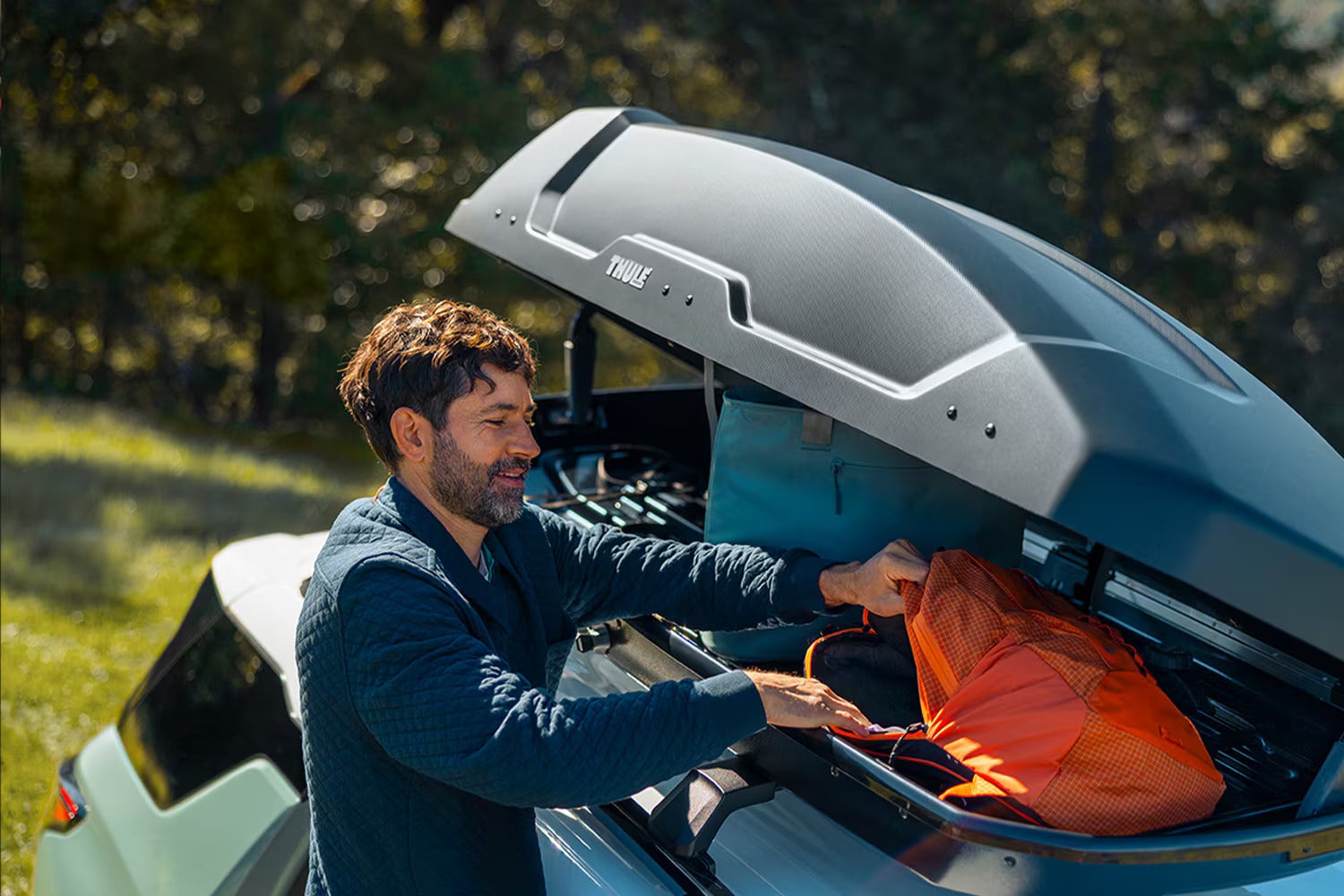 A man getting into the storage on top of an equinox.