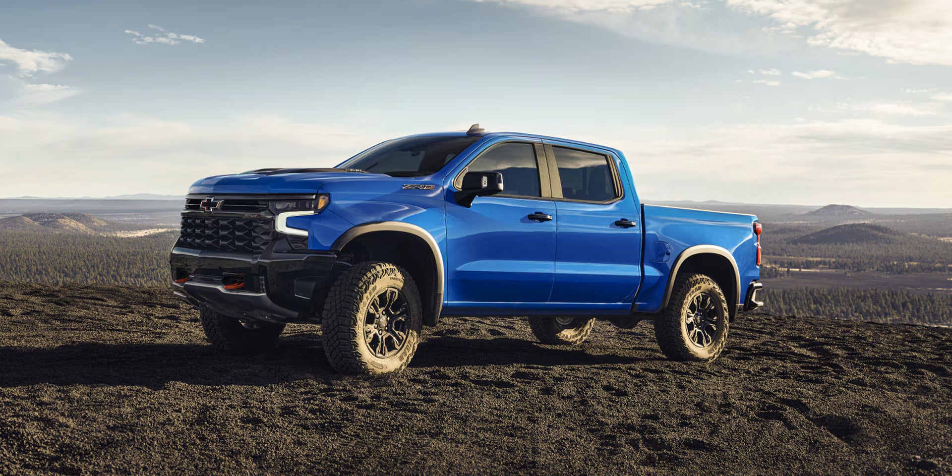A blue truck sitting off-road parked.