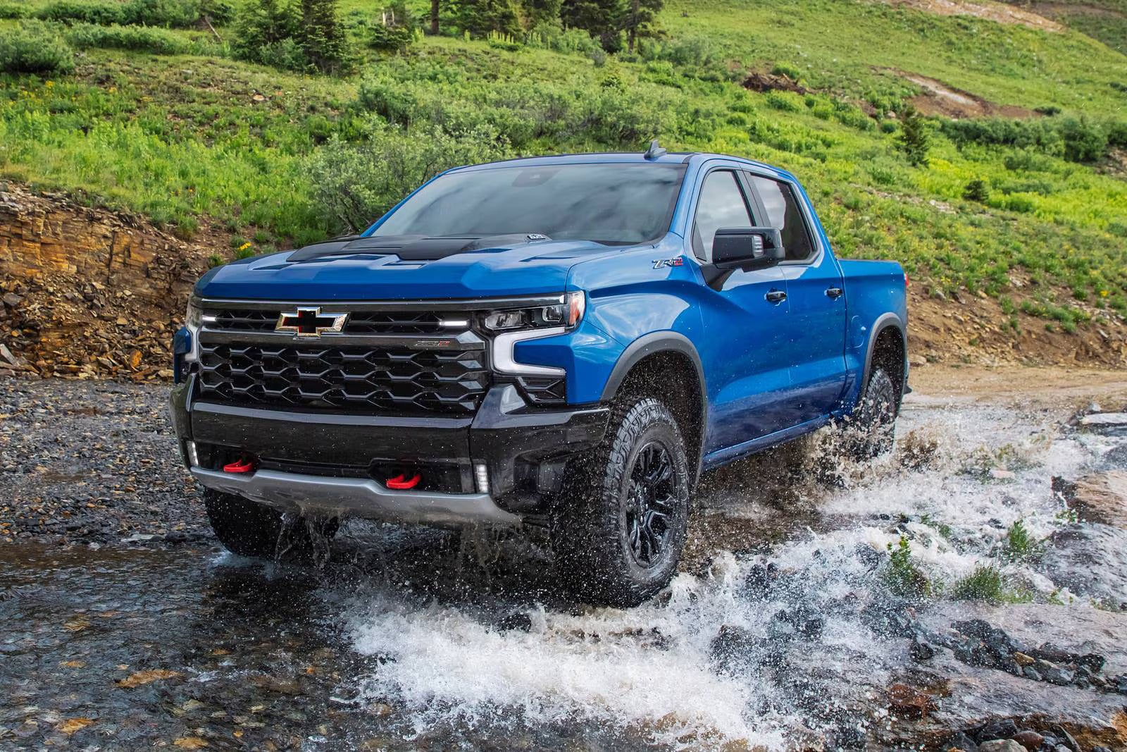 A blue truck driving through water.