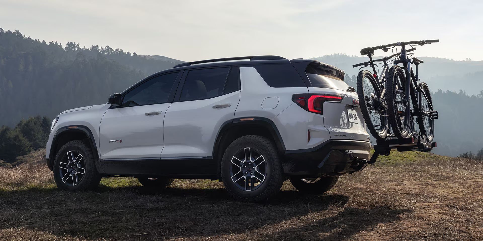 A white suv sitting with bikes on the back.