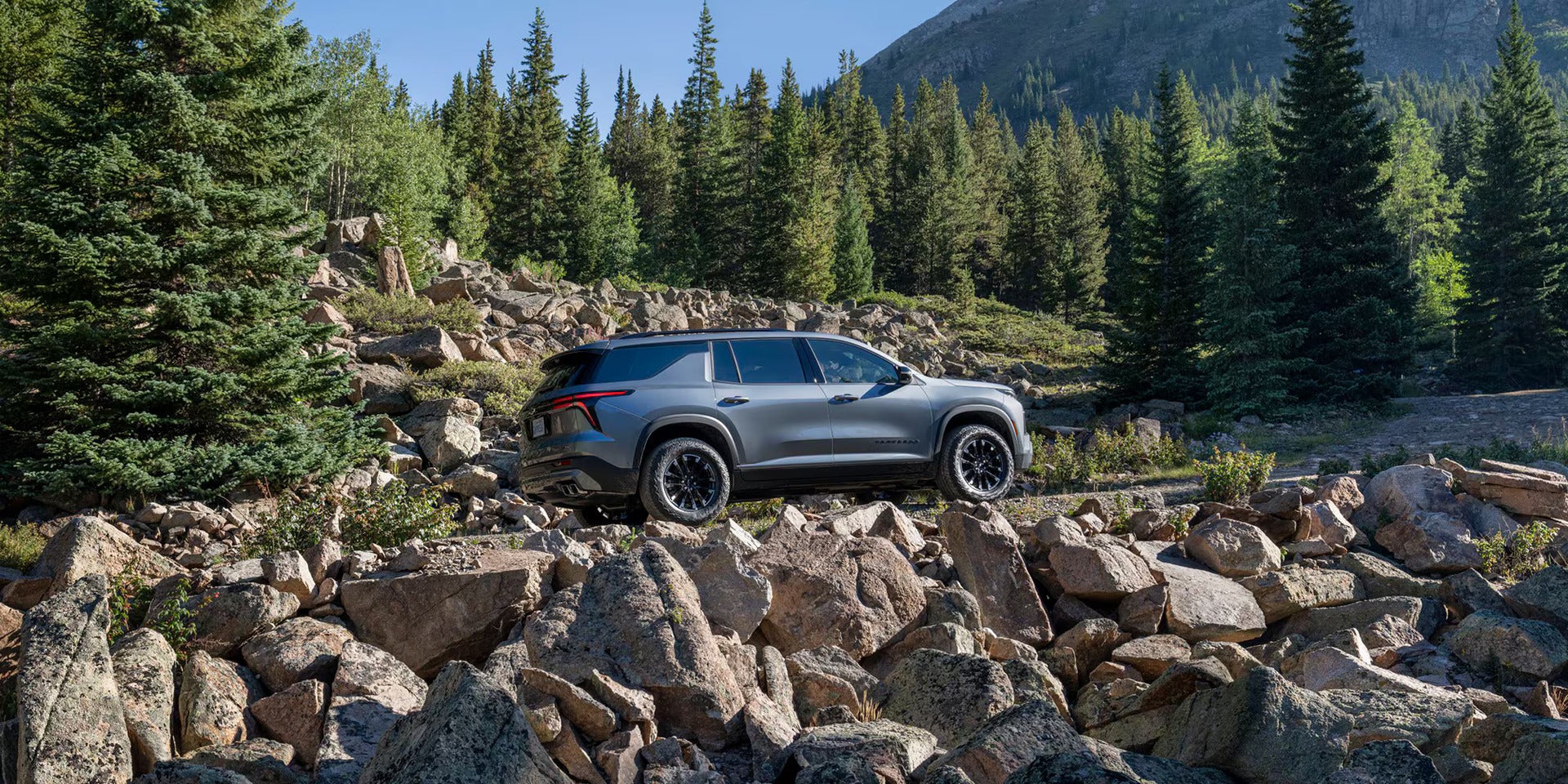 A silver suv driving up hill.