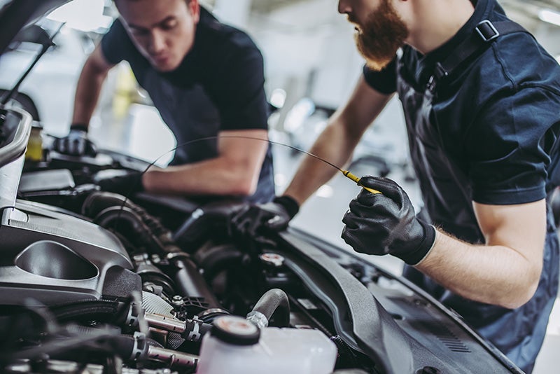 mechanics looking under the hood of a vehicle
