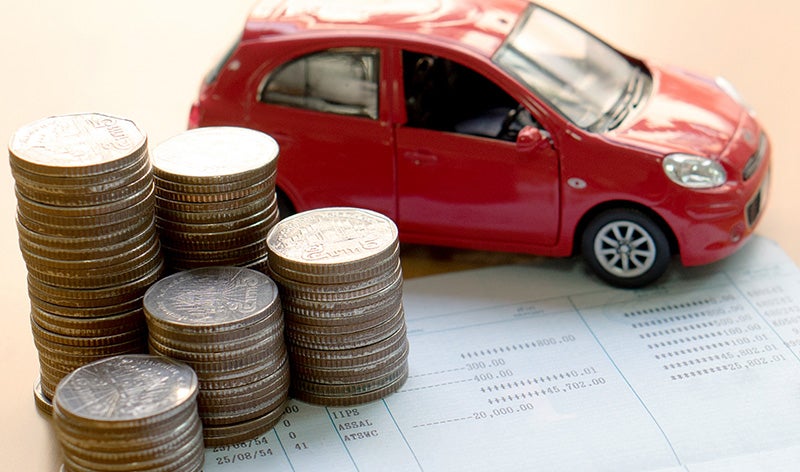 a small red car next to a stack of quarters with a piece of paper underneath